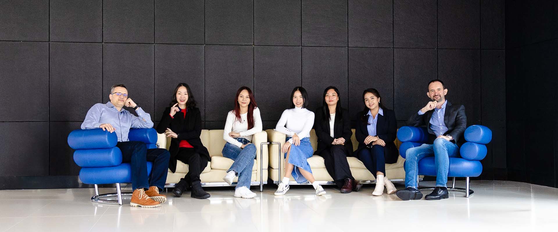 Thai team sitting on the blue chairs and posing.