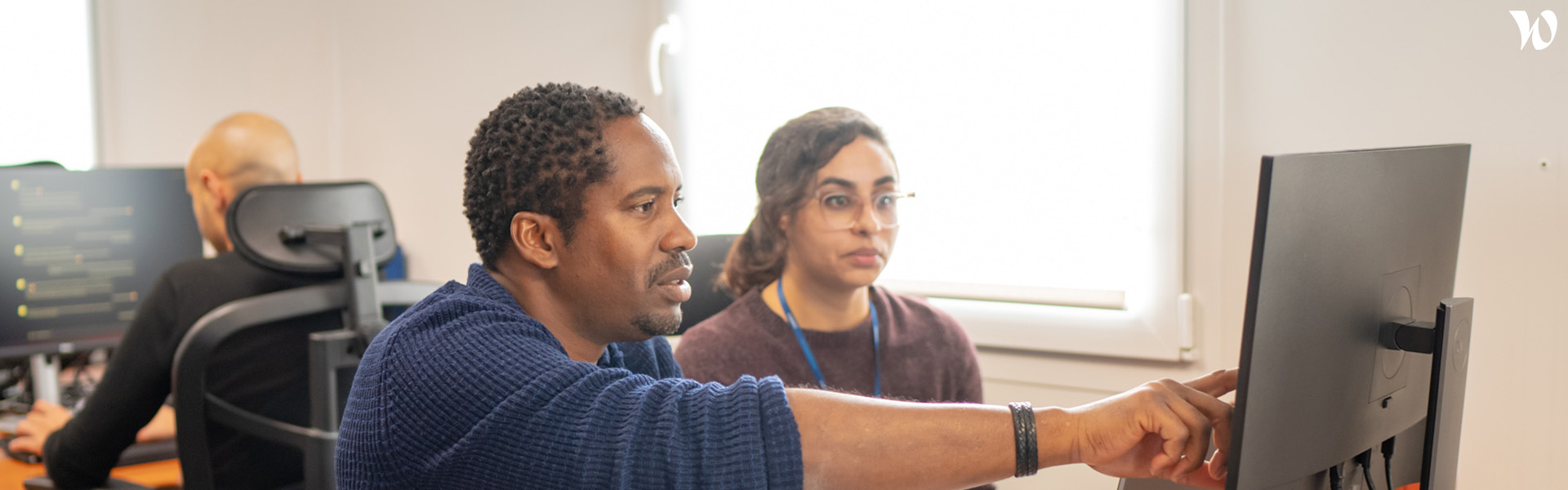 People working together, man explaining woman something on the computer.