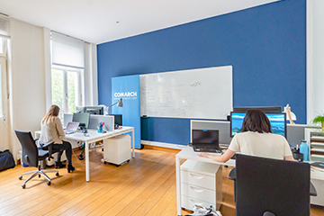 A picture of the company's office with the desks at which the employees are sitting