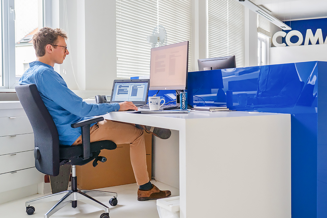 A young man sits in a desk chair and works with a computer