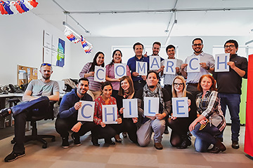 Agroup of employees at the company's headquarters holds a card with the inscription comarch chile
