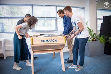 A group of young people play foosball in the office