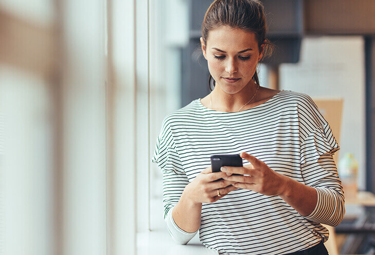 A young woman writes a message on the phone. She wonders if she sometimes suffers from FOMO