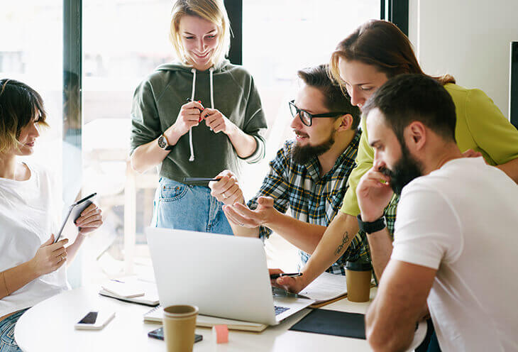 Young employees discuss together at the computer during a business meeting