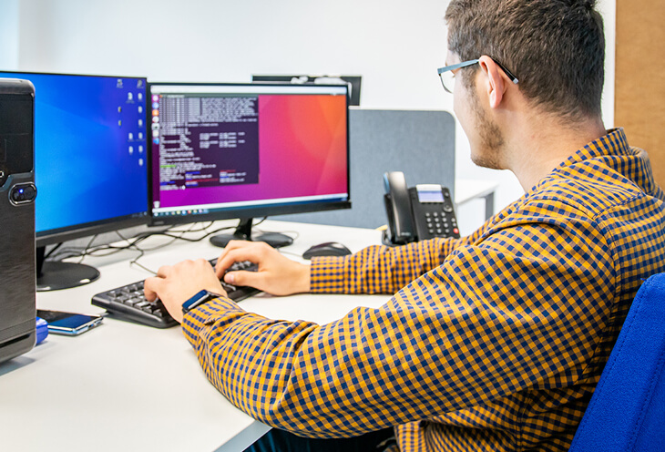 DevOps programmer works on a computer with two monitors.