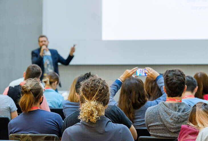 A group of young people are listening to a lecture at the GeeCon conference