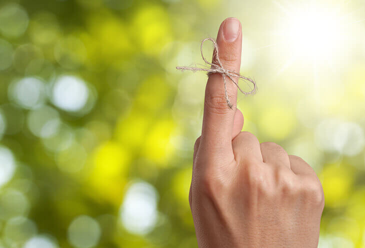 The forefinger on which the bow is wrapped in the background of the trees