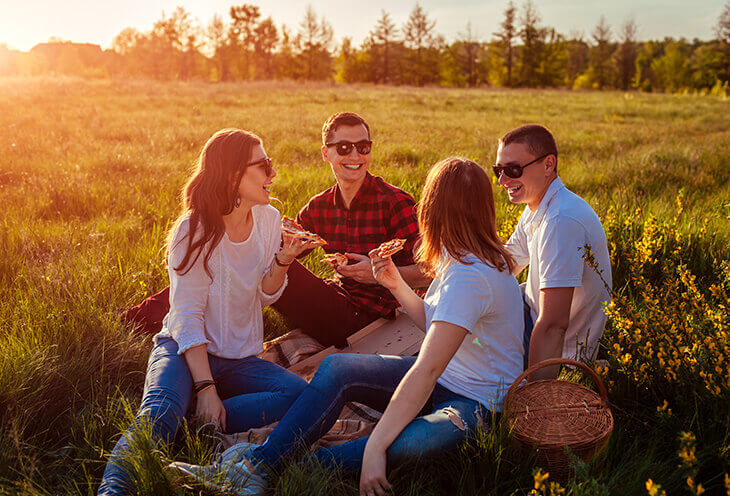 Jak wygląda work life balance? Grupka młodych ludzi rozmawia ze sobą podczas biwaku na polanie  